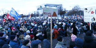 DemonstrantInnen stehen dicht gedrängt mit Flaggen und Schildern vor dem Bundeskanzleramt in Berlin