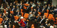 Abgeordnete sitzen im türkischen Parlament, manche von ihnen heben die Hand
