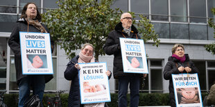 Mehrere Personen demonstrieren mit Plakaten.