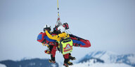 Ein verletzter Skifahrer wird mit zwei Sanitätern zum Hochschrauber hochgeseilt