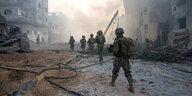 Eine Gruppe israelischer Soldaten geht durch eine zerstörte Straße, die von Ruinen gesäumt wird