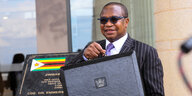 Simbabwes Finanzminister mit Sonnenbrille und Aktentasche