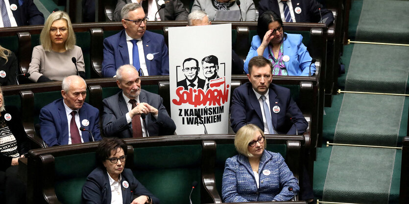 "Solidarität mit Mariusz Kaminski and Maciej Wasik" fordert ein Schild, das zwischen zwei Abgeordneten der PiS im polnischen Parlament steht