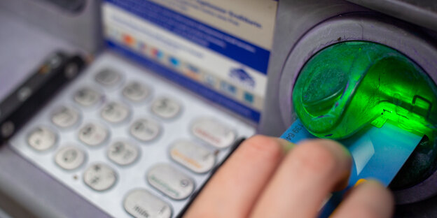 Eine Bankkundin steckt ihre Bankkarte in einen Geldautomaten