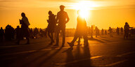 Menschen spazieren während des Sonnenuntergangs auf dem Tempelhofer Feld in Berlin