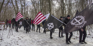 Menschen tragen Fahnen mit rechten Symbolen und gehen durch eine Schneelandschaft