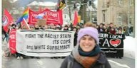 Die Abgeordnete Marie Kollenrott steht vor einem Banner mit der Aufschrift "fight the racist state, its cops and white supremacy"