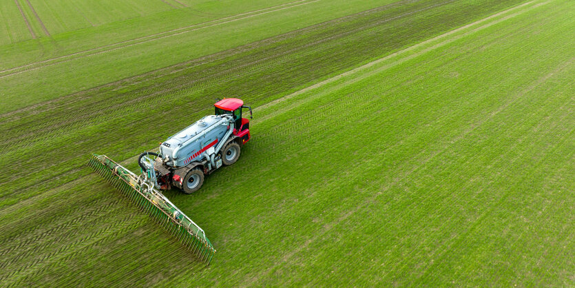 Ein Landwirt bringt mit seinem Gespann Gülle im sogenannten Schleppschuh Verfahren auf einem Feld aus.