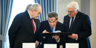 Zygmunt Stepinski, Marian Turski (M) und Frank-Walter Steinmeier schauen sich gemeinsam historische Fotos aus dem Warschauer Ghetto an