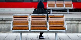 Ein Mensch sitzt am Bahnhof