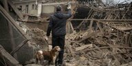 Ein Mann steht mit seinem Hund vor dem Trümmern seines Hauses.