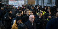 Kai Wegner läuft unter Polizeischutz durch eine Kreuzberger Straße, hinter ihm Demonstranten