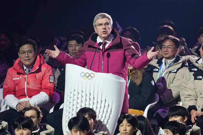 Thomas Bach am Rednerpult bei der Eröffnungszeremonie mit ausgebreiteten Armen