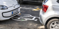 Zwei Autos parken einen Fahrradweg zu - in der Lücke zwischen den beiden Autos ist eine Fahrradwegmarkierung zu sehen