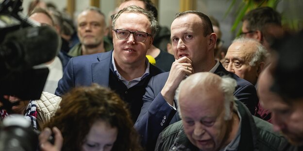 Christian Herrgott und Mario Voigtstehen in einer Menschenmenge und schauen gespannt auf das Auszählungsregebnis der Landratswahl