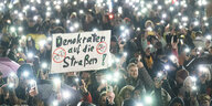 Menschen protestieren mit ihren Taschenlampen am Smartphone gegen die AfD - in der Mitte der Menge ein Schild: Demokraten auf die Straßen