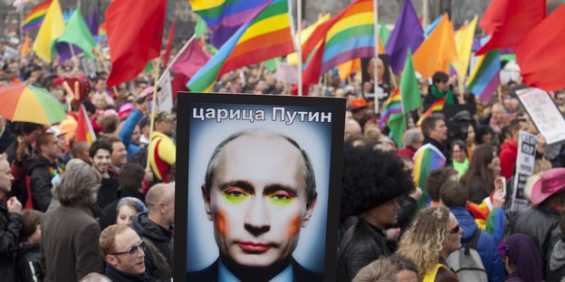 Eine Demonstration. Regenbogen-Flaggen und ein Bild mit Putins geschminktem Gesicht.