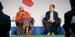 Claudia Roth und Philipp Lahm sitzen auf einem Podium nebeneinander