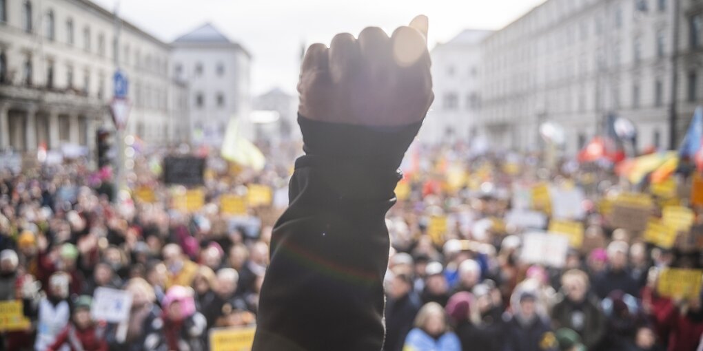 Eine Faust wird gereckt, im Hintergrund eine Menschenmenge