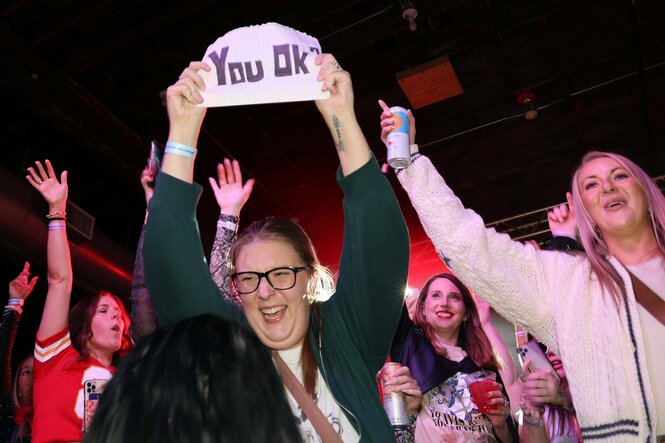 Frauen recken ausgelassen die Arme in die Höhe, eine zeigt ein SChild Your ok