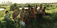 Eine Roma-Familie sitzt auf einer Wiese.
