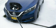 Eiszapfen hängen an einem Elektrofahrzeug, das an einer Ladestation geparkt ist.