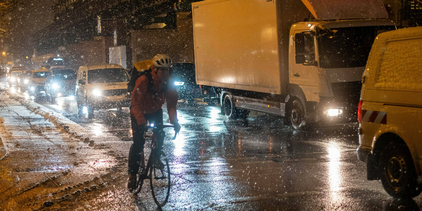 Radfahrer bei Schneefall neben Autos