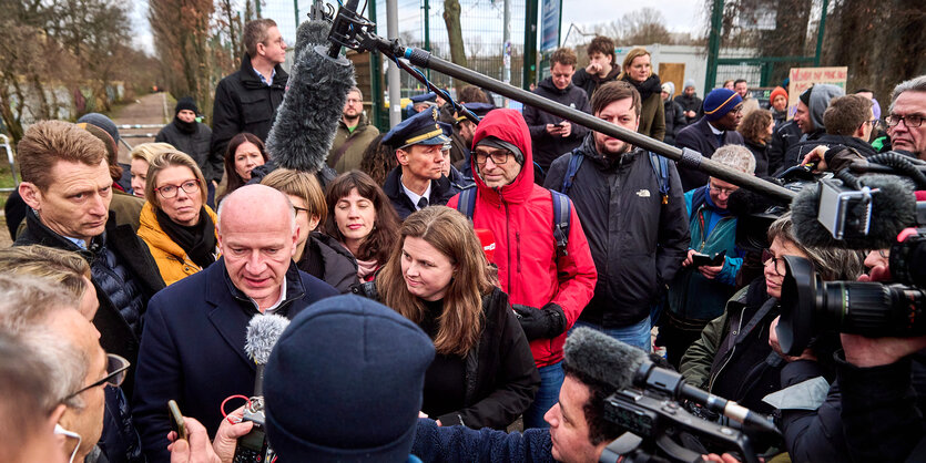 Kai Wegner und Clara Herrmann von Medien umzingelt von Journalisten und Anwohnern