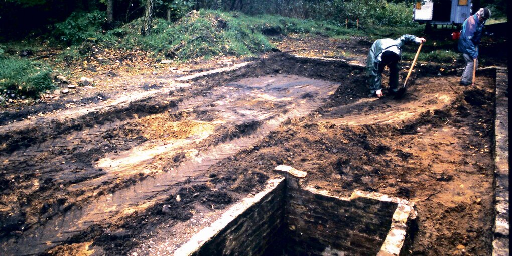 Auf dem Foto aus den 90ern sieht man zwei Menschen, die in einem Waldstück graben