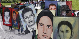 Teilnehmer eines Trauermarsches anlässlich des Jahrestages halten Portraits der Verschwundenen.