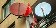 An einem Balkon sind zwei Satelitenschüssel und zwei kleine türkische Flaggen angebracht