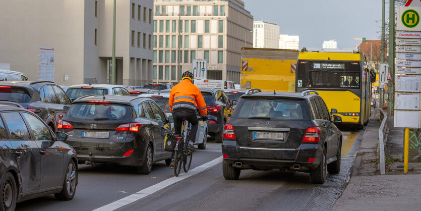 Radfahrende Person auf Straße zwischen vielen Autos