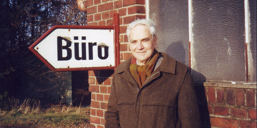 Der Schriftsteller J. J. Voskuil steht vor einem Schild mit der Aufschrift Büro