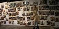Eine Frau steht vor einer Fotowand, auf der die vermissten Hamas-Geiseln zu sehen sind.