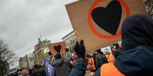 Aktivisten der letzten Generation halten Plakate mit Herzen in die Höhe