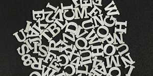 Verschiedene Buchstaben vor schwarzen Untergrund, ein Symbolbild für eine Lese- und Schreibeschwäche