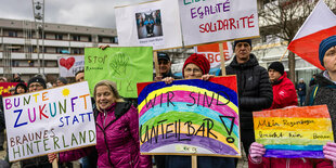 Menschen stehen mit bunten Schildern auf der Straße