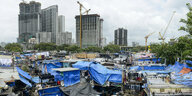 Ein Slum mit Wäschereien und in Hintergrund Neubau von Hochhäusern in Mumbai, Indien.