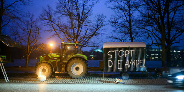 Ein Traktor in der Dämmerung und ein Bauwagen mit der Aufschrift"Stopt die Ampel"
