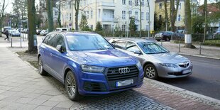 Blaues Auto parkt auf dem Bürgersteig.