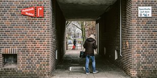 An einer Hauswand hängt neben einem Durchgang ein Schild mit der Aufschrift "Poliklinik".