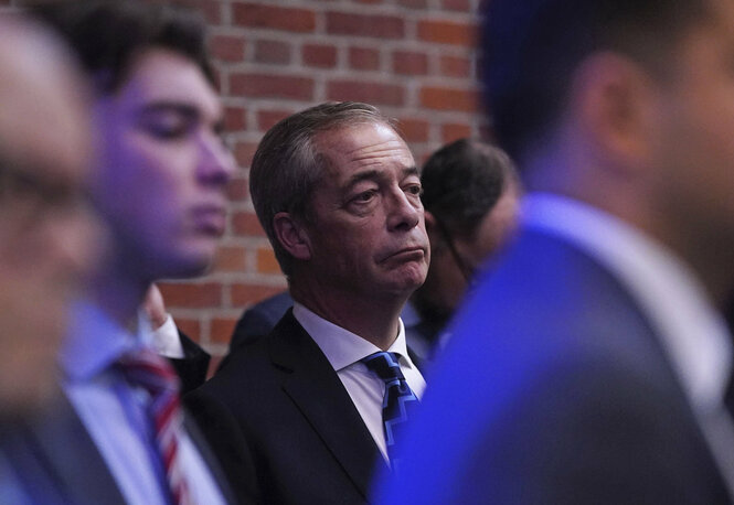 Nigel Farage trägt Anzug und Krawatte, zieht die Augenbrauen hoch und die Mundwinkel runter.