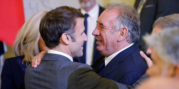 Emmanuel Macron und Francois Bayrou umarmen sich freundschafllich während einer Veranstaltung.