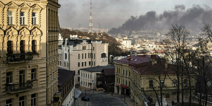 Ein Kyjiwer Stadtteil, im Hintergrund steigt eine Rauchwolke auf