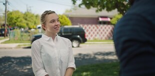 Reality (Sydney Sweeney) steht vor einer Vorstadtstraße