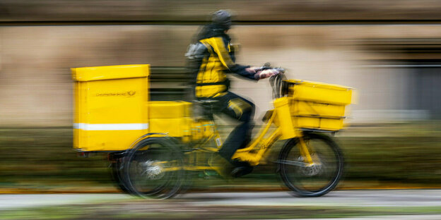 Ein Postbot*in der Deutschen Post fährt auf einem Lastenrad.