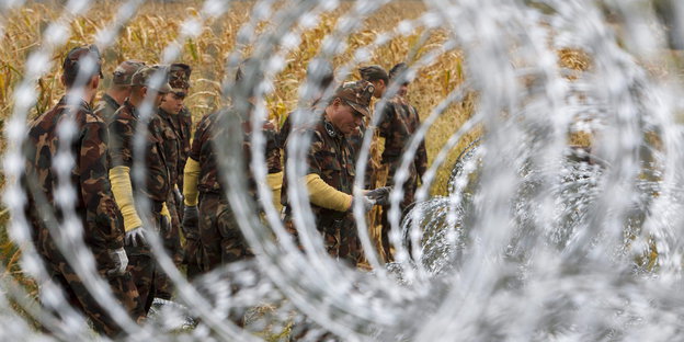 Soldaten vor einem Zaun aus Nato-Draht