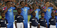 Vier Spieler der DR Kongo halten sich, während die Hymne gespielt wird, eine Hand vor den Mund und zeigen mit zwei Fingern der anderen Hand auf ihrer Schläfen
