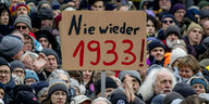 Eine Menschenmenge und ein Schild auf dem zu lesen ist: "Nie wieder 1933"