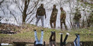 4 junge Männer spiegeln sich in einer Pfütze, das Bild steht auf dem Kopf